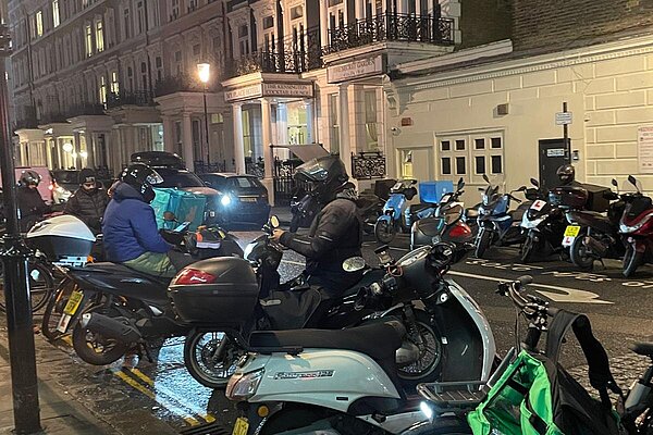 A line of delivery bikes parked on a road at night